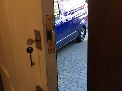 Wooden door with key in secure mortice lock. Locksmith van outside